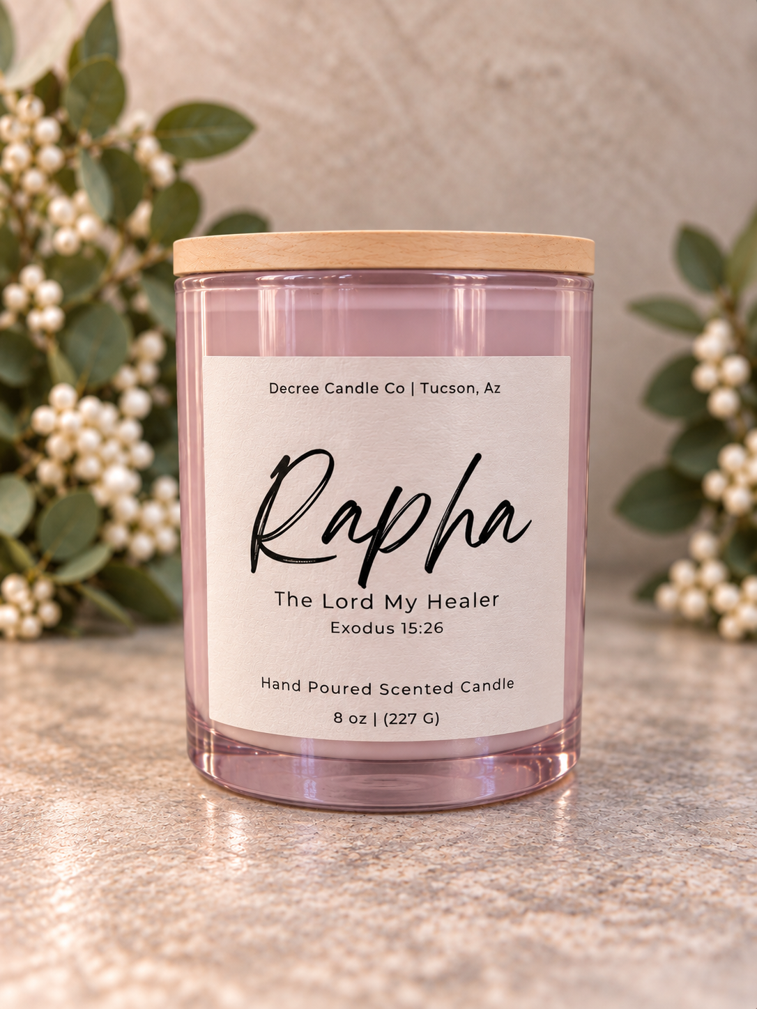 Rapha Scripture-inspired candle by Decree Candle Co. in a soft pink glass jar with a wood lid.