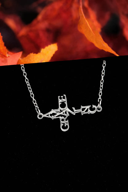 Silver Amazing Grace script cross bracelet displayed with autumn leaves