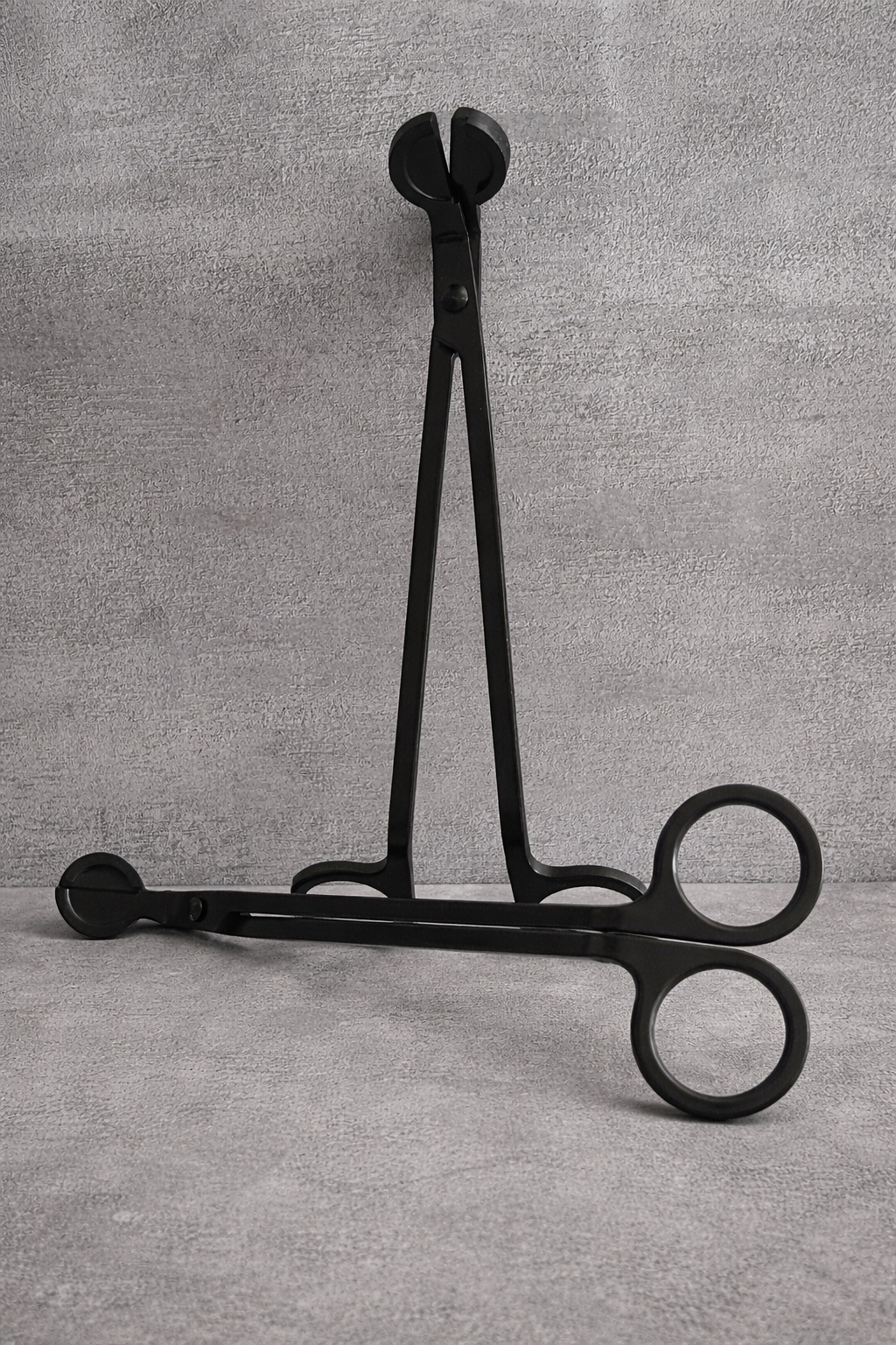 Black metal candle wick trimmer with angled handle and debris-catching tray