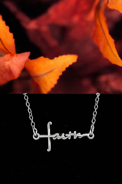 Silver Faith script cross bracelet displayed with autumn leaves