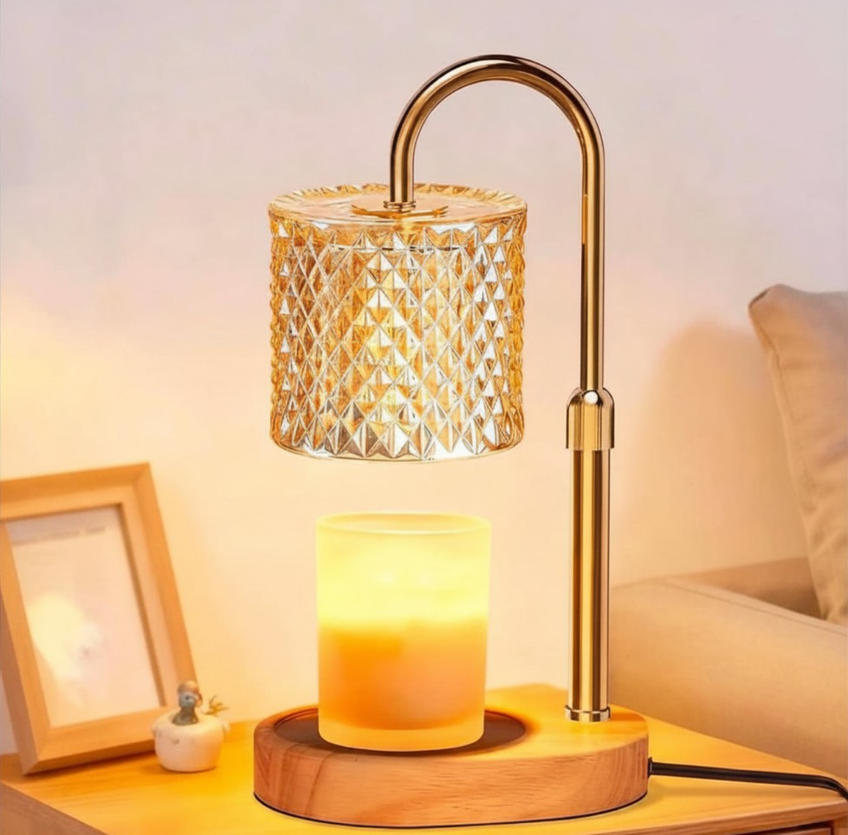 Gold candle warmer lamp with a gold glass shade and wooden base warming a jar candle