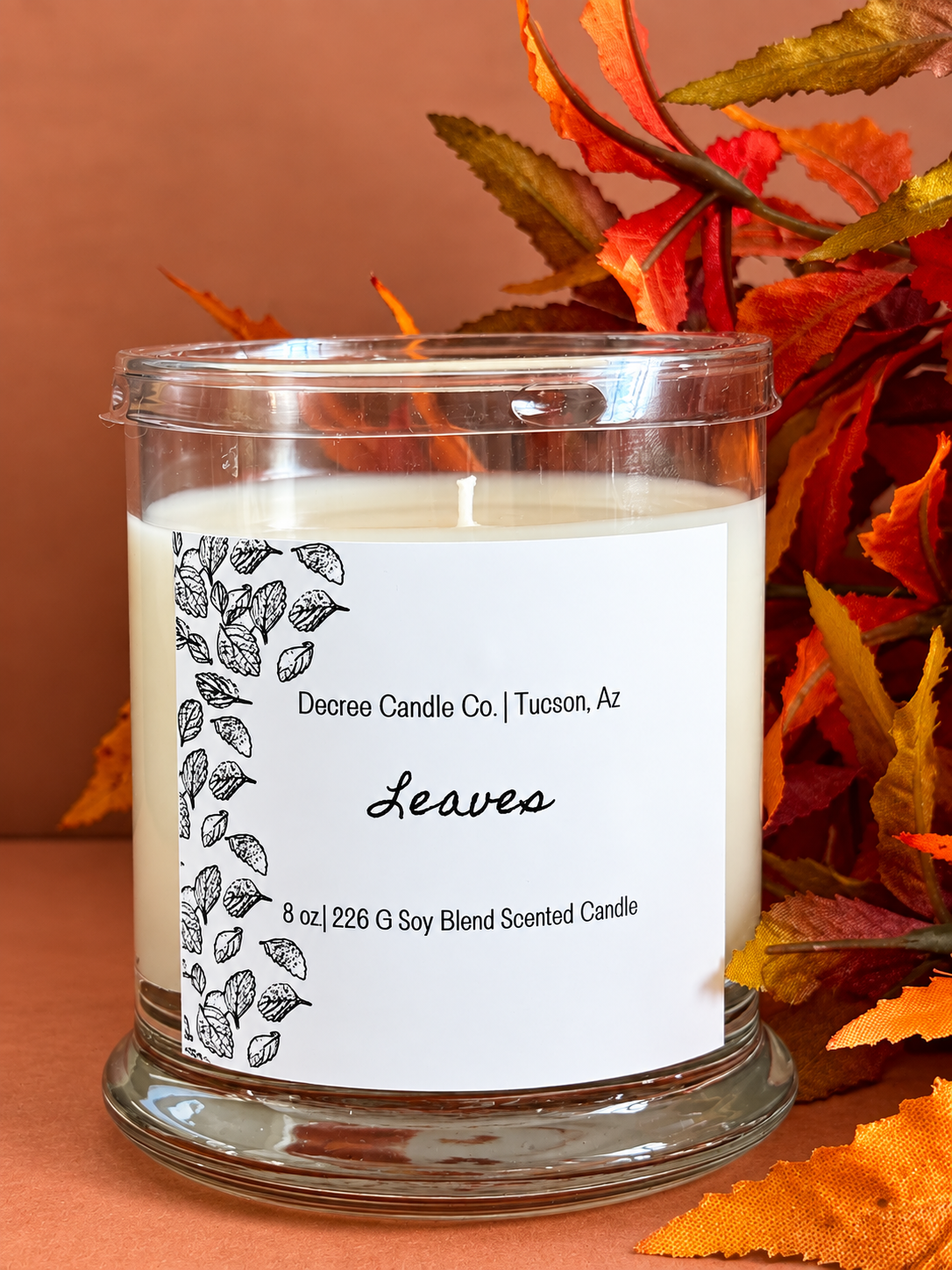 Leaves fall scented candle by Decree Candle Co. styled with colorful autumn leaves