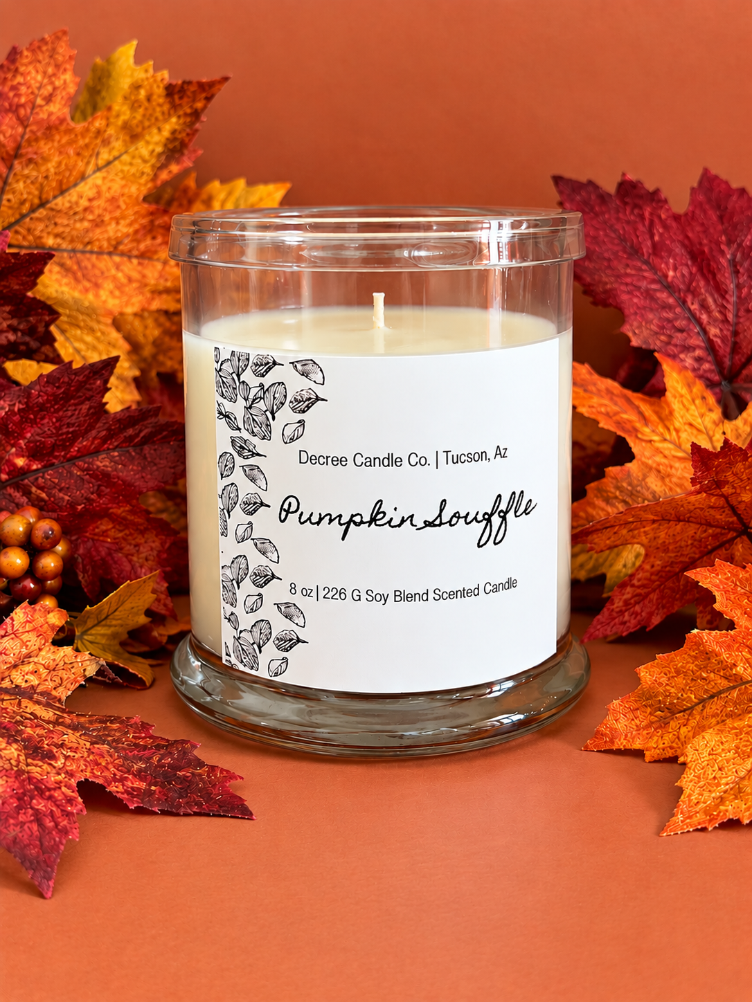 Pumpkin Souffle fall scented candle by Decree Candle Co. styled with colorful autumn leaves